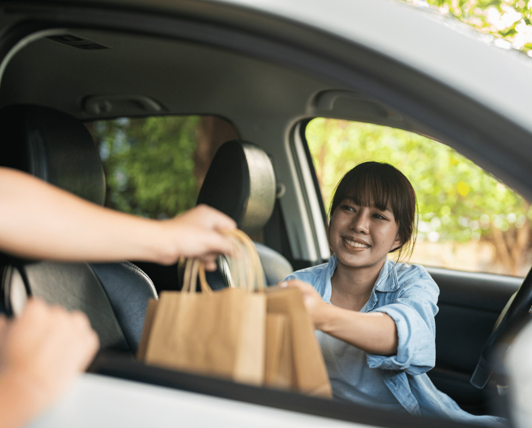 restaurant staff handing off curbside food pickup to a woman in a car