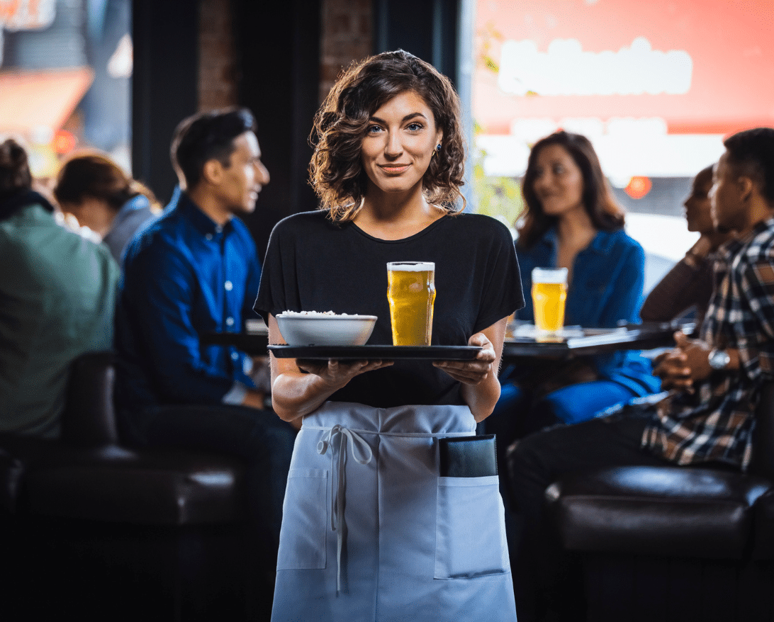 waitress holding a tray of drinks and food at a restaurant; understanding server minimum wage