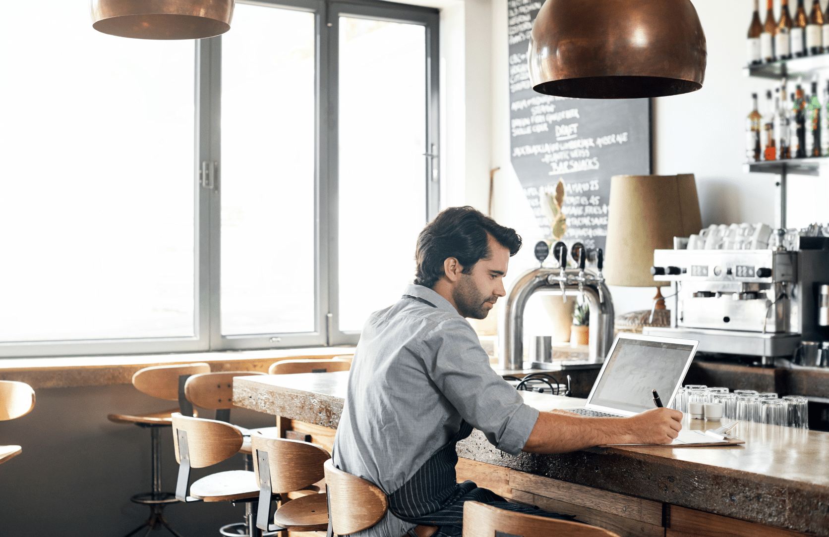 Restaurant owner reviewing business on laptop at the bar